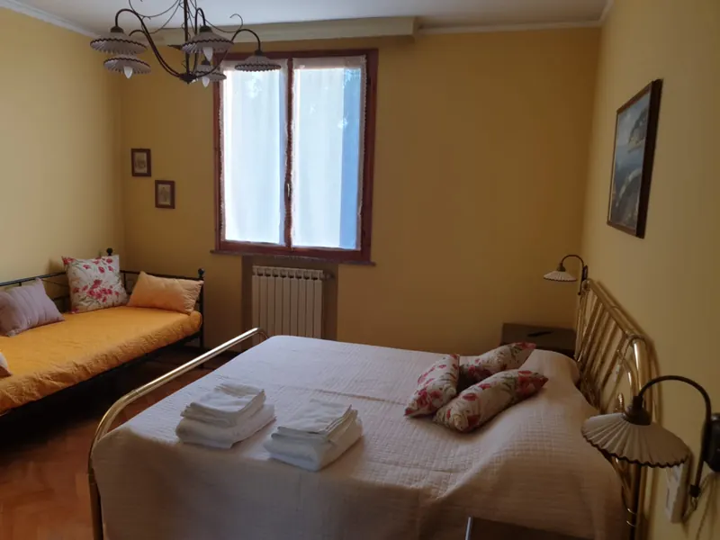 Camera Ambra con pareti color miele, letto matrimoniale e divanetto